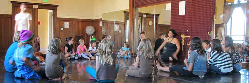 Amy Marie with a big circle of kids at a rehearsal